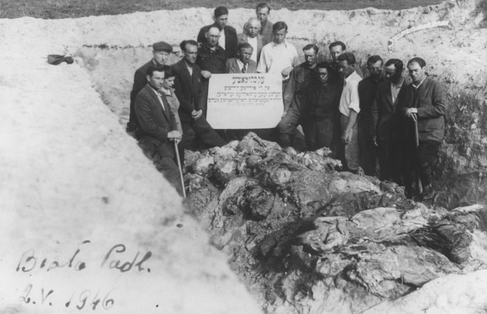 Jewish survivors stand in an opened mass grave among the exhumed bodies of the victims of a mass shooting in Biala Podlaska